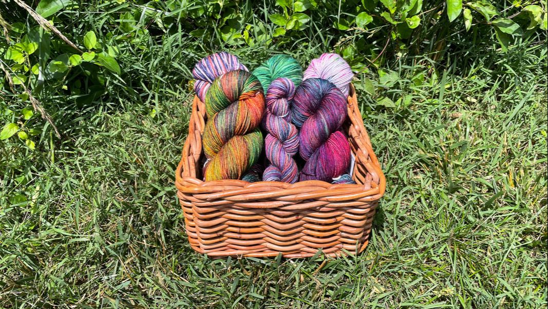basket of fingering weight yarn in the grass